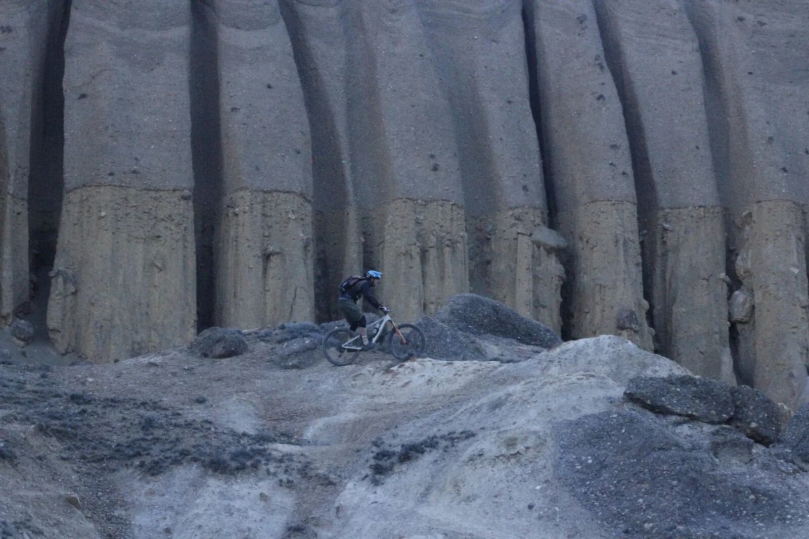 A mountain biker rides beneath tall fluted cliffs eroded into organ-pipe columns.